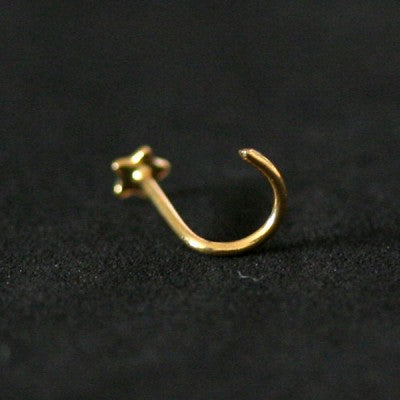 piercing nostril folheado a ouro da tal da realeza em um fundo preto aveludado. a peça tem formato de estrela na ponta.