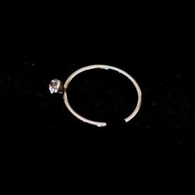 piercing nostril argola em aço cirúrgico da tal da realeza em um fundo preto aveludado. a peça também possui uma pedra brilhante.