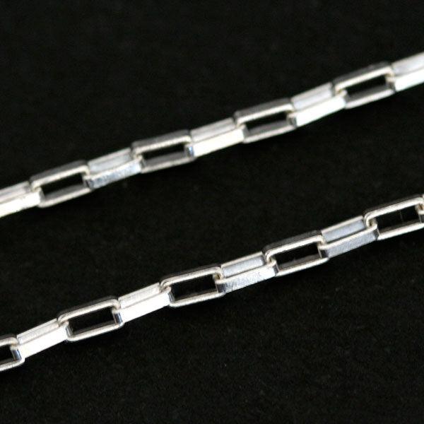 corrente de prata 925 com elos cartier em uma superfície preta . a imagem destaca os elos da correntes, que possuem 2mm.