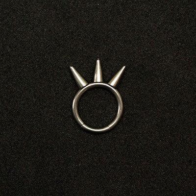 piercing segment da tal da realeza em um fundo preto aveludado. a peça é prateada, tem formato circular e possui 3 spikes.