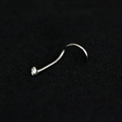 Piercing Nostril em aço cirúrgico da Tal da Realeza em um fundo preto aveludado. A peça tem uma pedra cravada na ponta.