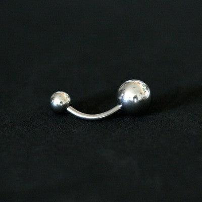 Piercing de umbigo da Tal da Realeza em um fundo preto aveludado,. A peça é feita de aço cirúrgico e possui esferas nas extremidades.
