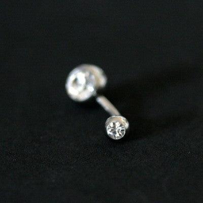 Piercing de umbigo da Tal da Realeza visto de frente em um fundo preto aveludado. A peça é feita de aço cirúrgico e conta com pedras de cristal nas extremidades.