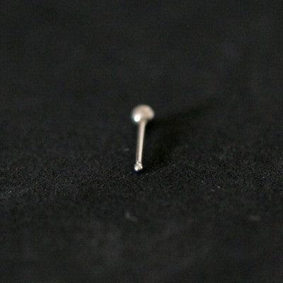 piercing nostril em aço cirúrgico da tal da realeza em um fundo preto aveludado. a peça tem formato uma pedra de cristal na ponta.