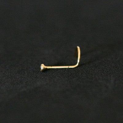 Piercing Nostril folheado a ouro da Tal da Realeza em um fundo preto aveludado. A peça tem uma pedra de cristal na ponta.