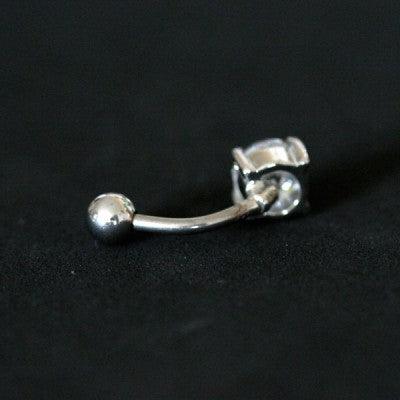 Piercing de umbigo da Tal da Realeza visto por trás em um fundo preto aveludado. A peça é feita de aço cirúrgico e conta com uma pedra de zircônia.