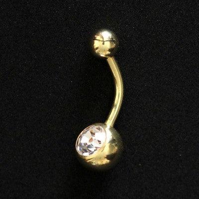 Piercing de umbigo da Tal da Realeza em um fundo preto aveludado. A peça é dourada e conta com uma pedra de cristal em uma das extremidades.