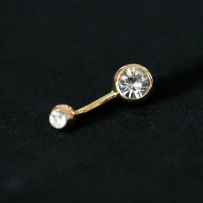 Piercing de umbigo da Tal da Realeza em um fundo preto aveludado. A peça possui cristais nas extremidades, que são em formato de esferas.