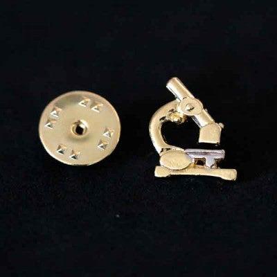 Broche Biomedicina folheado a ouro em um fundo preto. A peça tem formato de um microscópio.