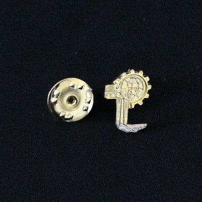 Broche Engenharia de Produção folheado a ouro em um fundo preto. A peça tem formato de engrenagem, com uma fábrica ao centro.