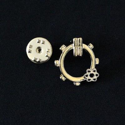 Broche Engenharia Química folheado a ouro em um fundo preto. A peça tem formato de engrenagem, com um átomo no canto inferior.