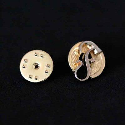 Broche Fonoaduiologia folheado a ouro em um fundo preto. A peça tem formato circular, com uma letra F ao centro.