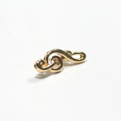 Broche Música folheado a ouro em um fundo branco. A peça possui formato da nota musical clave de sol.