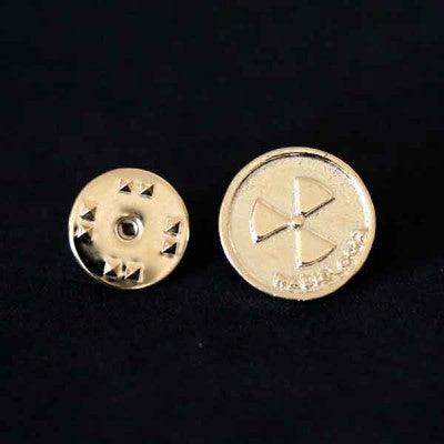 Broche Radiologia folheado a ouro em um fundo preto. A peça é circular, com o símbolo de radiação e a palavra Radiologia.