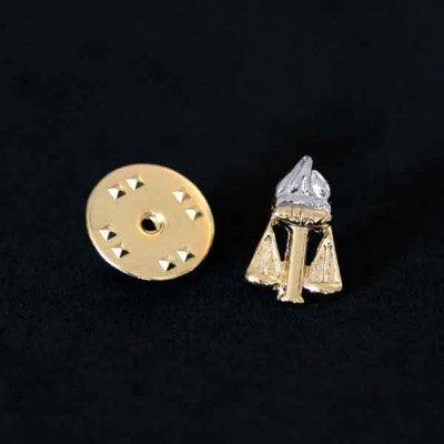 Broche Serviço Social folheado a ouro em um fundo preto. O formato da peça representa a união entre uma tocha e uma balança.