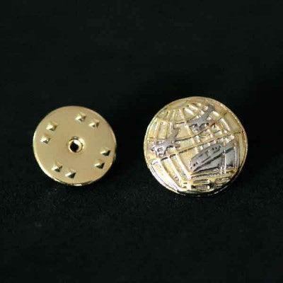 Broche Turismo folheado a ouro em um fundo preto. A peça tem formato de um globo terrestre.