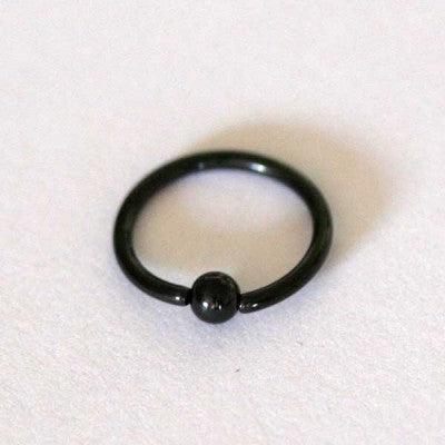 Piercing Captive Esfera da Tal da Realeza em um fundo branco aveludado. A peça é preta, tem formato circular e possui um detalhe em formato esférico.