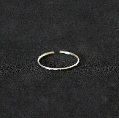 Piercing Nostril em aço cirúrgico da Tal da Realeza em um fundo preto aveludado. A peça tem formato de argola.