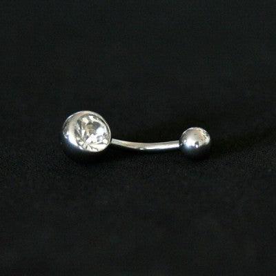 Piercing de umbigo da Tal da Realeza visto de frente em um fundo preto aveludado. A peça é feita de aço cirúrgico e conta com uma pedra de cristal  em uma das extremidades.