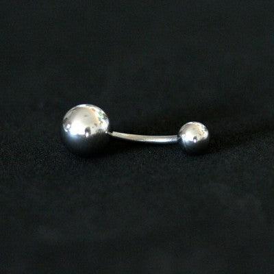 Piercing de umbigo da Tal da Realeza em um fundo preto aveludado,. A peça é feita de aço cirúrgico e possui esferas nas extremidades.