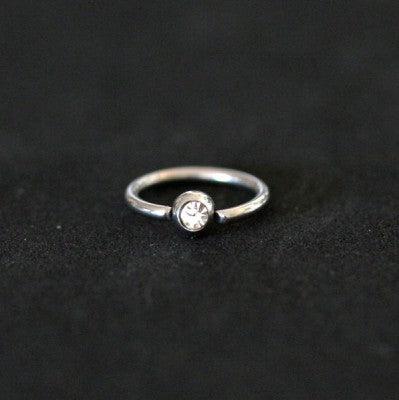 Piercing Captive Esfera da Tal da Realeza em um fundo branco aveludado. A peça é prateada, tem formato circular e possui um detalhe esférico com pedra de cristal.