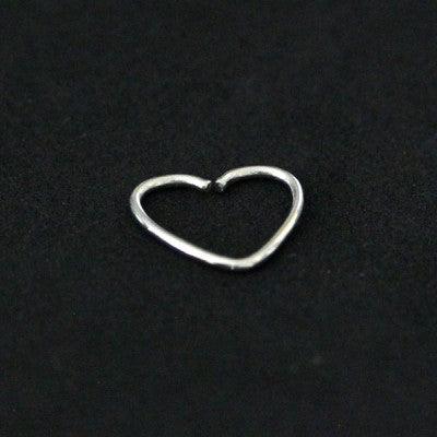 Piercing Tragus em aço cirúrgico da Tal da Realeza em um fundo preto aveludado. A peça tem formato de um coração.