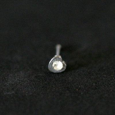 Piercing Nostril em aço cirúrgico da Tal da Realeza em um fundo preto aveludado. A peça tem formato de coração na ponta, com uma pedra de cristal.