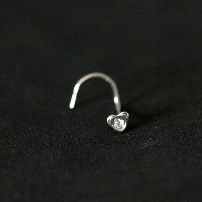 Piercing Nostril em aço cirúrgico da Tal da Realeza em um fundo preto aveludado. A peça tem formato de coração na ponta, com uma pedra de cristal.