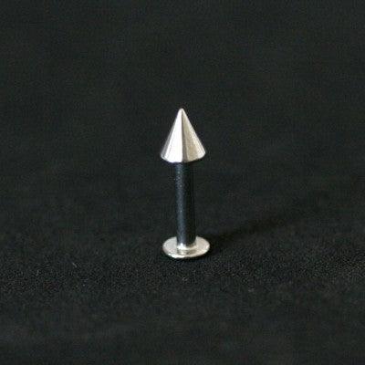 piercing labret da tal da realeza em um fundo preto aveludado. a peça é prateada e possui spike na extremidade.