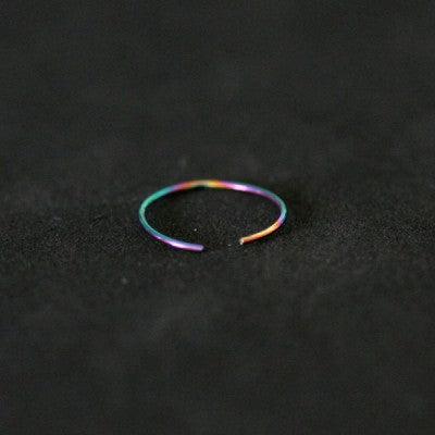 Piercing Nostril em aço cirúrgico da Tal da Realeza em um fundo preto aveludado. A peça é colorida e tem formato de argola.