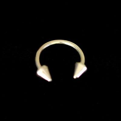 Piercing Barbell da Tal da Realeza em um fundo preto aveludado. A peça é dourada, tem formato de ferradura e possui spikes nas extremidades.