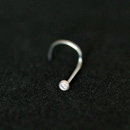 Piercing Nostril em aço cirúrgico da Tal da Realeza em um fundo preto aveludado. A peça tem uma pedra de zircônia na ponta.