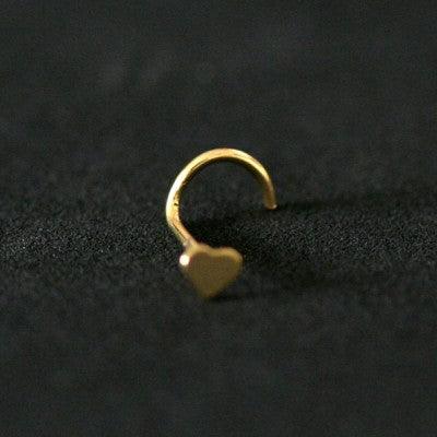 Piercing Nostril folheado a ouro da Tal da Realeza em um fundo preto aveludado. A peça tem formato de coração na ponta.