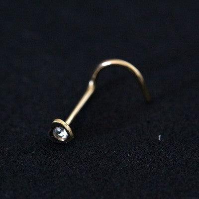 Piercing Nostril folheado a ouro da Tal da Realeza em um fundo preto aveludado. A peça tem formato de coração e uma pedra de zircônia.