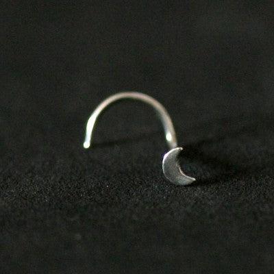 Piercing Nostril em aço cirúrgico da Tal da Realeza em um fundo preto aveludado. A peça tem formato de lua na ponta.