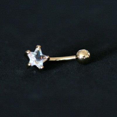 Piercing de umbigo da Tal da Realeza visto de frente em um fundo preto aveludado. A peça é dourada e conta com uma pedra de zircônia.
