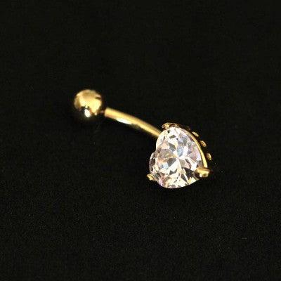 Piercing de umbigo da Tal da Realeza em um fundo preto aveludado. A peça é dourada e conta com uma zircônia em formato de coração em uma das extremidades.